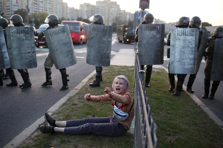 A woman reacts while sitting on the ground near Belarusian law enforcement officers dispersing a crowd during a protest against the inauguration of President Alexander Lukashenko in Minsk, Belarus. Tut.By via REUTERS